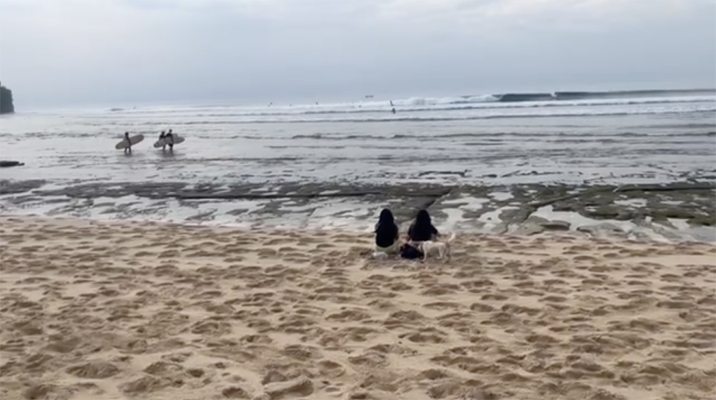 Denize karşı oturan iki kişi, geniş bir kıyı manzarası