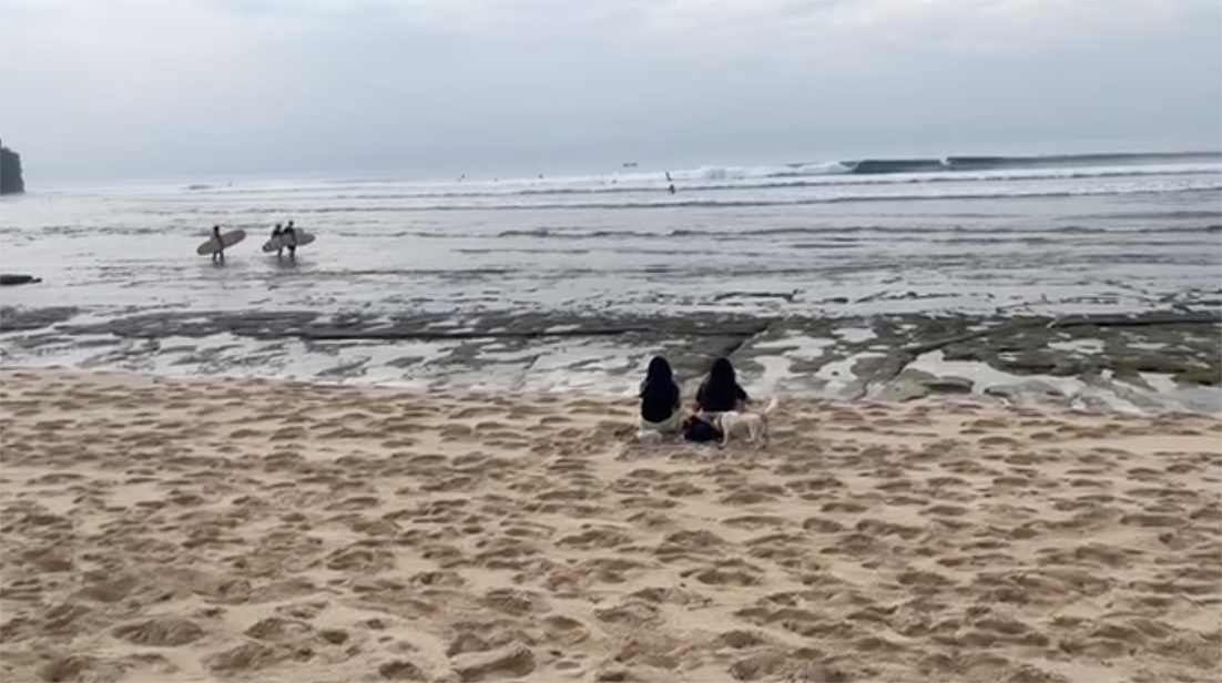 Denize karşı oturan iki kişi, geniş bir kıyı manzarası